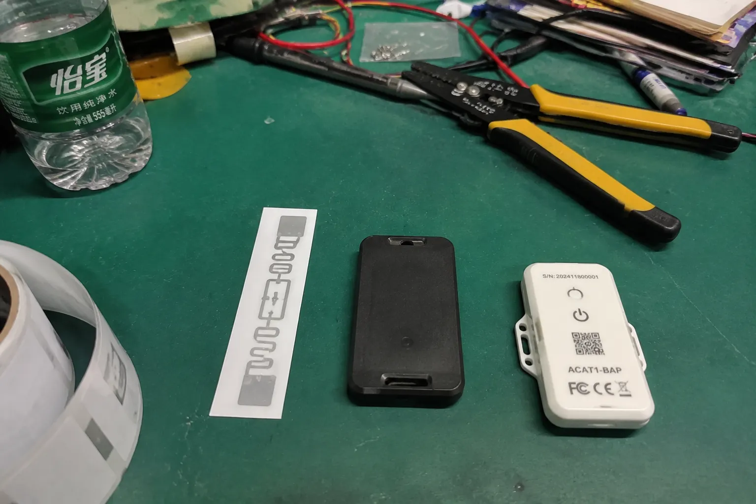 Three Fongwah RFID tag types passive inlay active beacon and BAP sensor tag on a laboratory workbench.