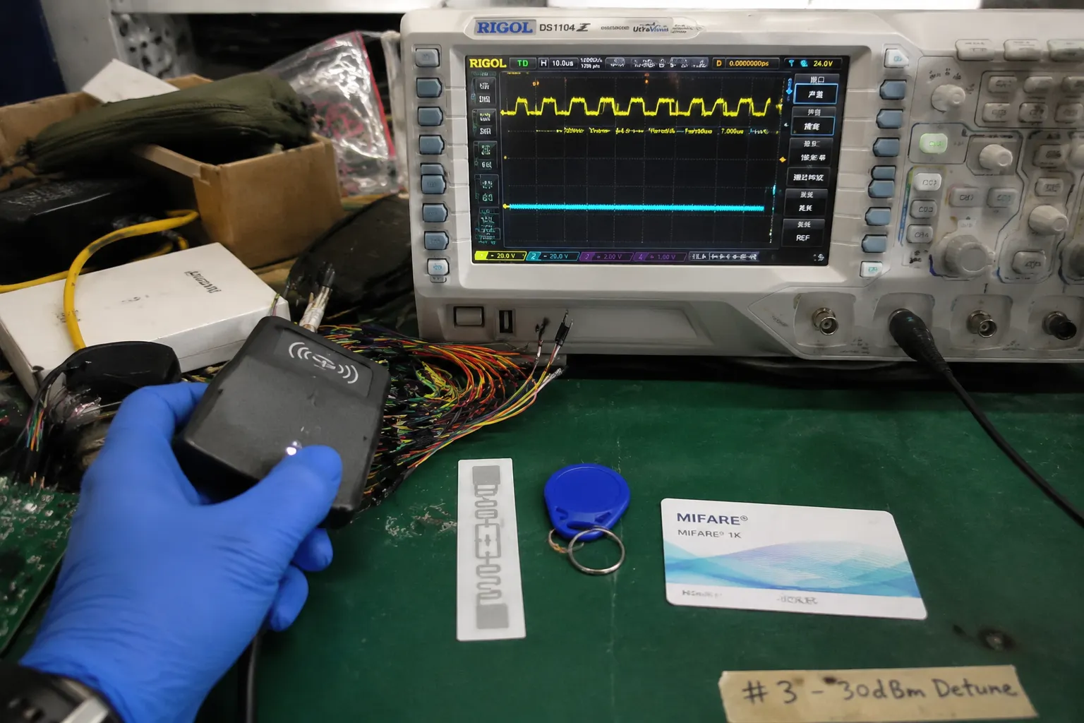 Fongwah engineer comparing LF HF and UHF RFID tag frequency bands on a test bench with an oscilloscope.