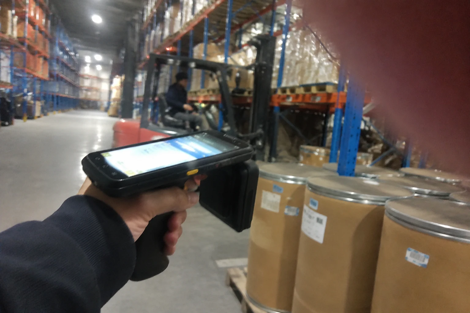 Fongwah engineer carrying out an RFID site survey using a handheld reader in a steel warehouse aisle.
