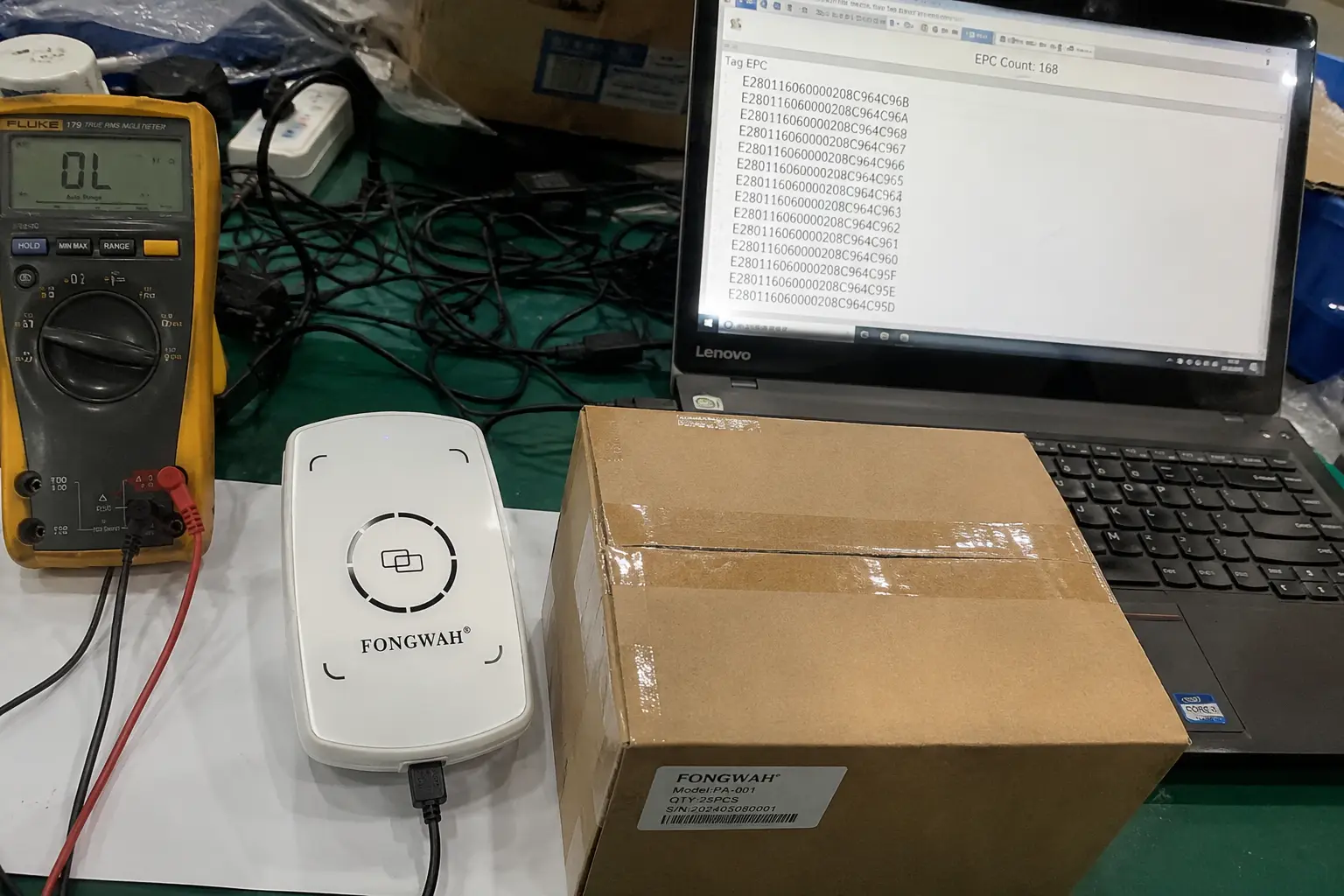 Fongwah desktop USB RFID reader scanning a cardboard box filled with tagged apparel on a workbench.