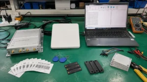 Comprehensive showcase of the four RFID system components including UHF tags, reader module, patch antenna, and laptop software on a test bench.