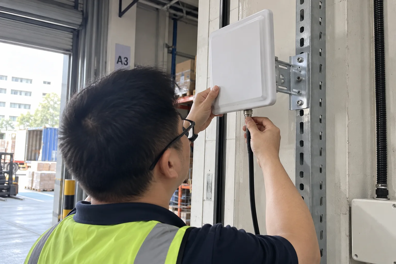 A technician checking the antenna connection on an RFID reader
