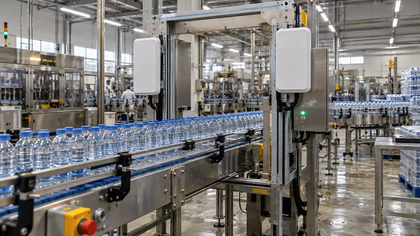 High-speed packaging conveyor moving clear filled liquid bottles through a fixed RFID reader antenna station.