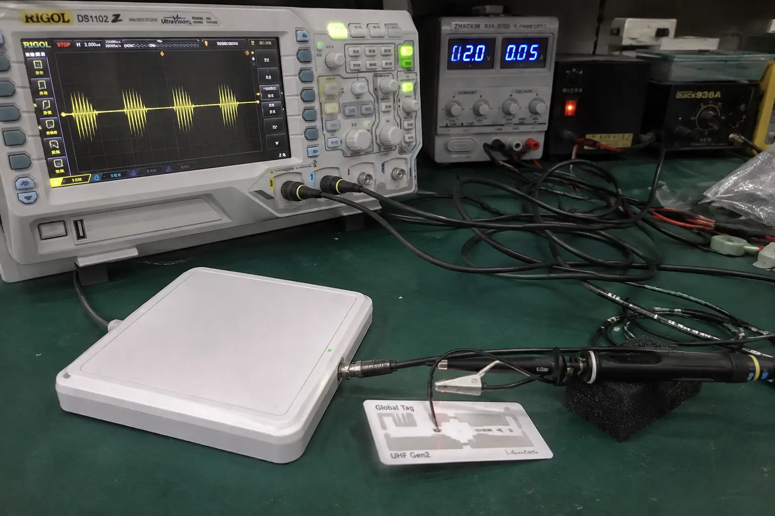 Testing passive UHF RFID tag backscatter modulation using an oscilloscope and reader antenna on a laboratory bench.