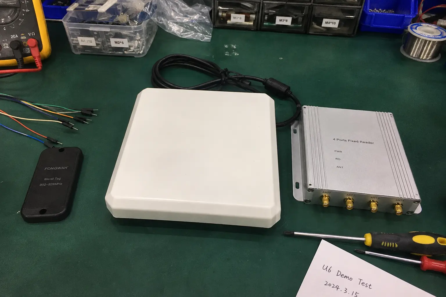 Close-up of three core RFID hardware components: a UHF PCB on-metal tag, a panel antenna, and a fixed reader module.