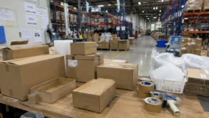 Busy logistics fulfillment center packing station with cardboard boxes ready for dispatch.
