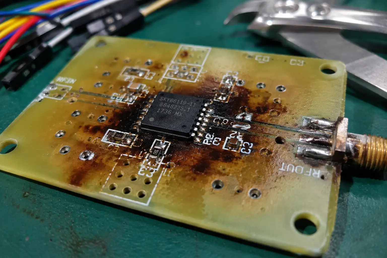 Teardown matrix showing scorched PCB substrate around an un-sunk RF power amplifier after continuous wave encoding tests