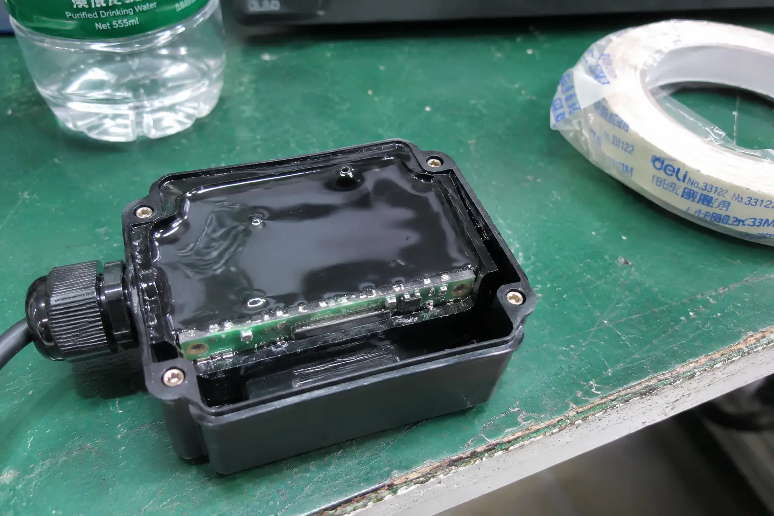 A cutaway view of an RFID reader module showing the solid black resin potting completely encasing the circuit board for waterproofing