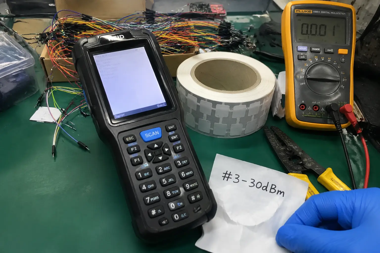 Fongwah handheld RFID reader performing high-density retail bulk encoding diagnostics on a messy Shenzhen hardware lab workbench